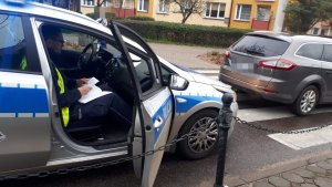 Zdjęcie radiowozu z policjantem z siedzącym na miejscu pasażera.