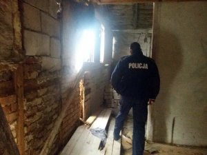 Zdjęcie przedstawiające policjanta sprawdzającego pustostan w którym mogą przebywać osoby bezdomne.