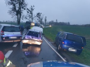 Zdjęcie odcinka drogi na którym doszło do kolizji, trasa Kwidzyn Gardeja i widok trzech samochodów biorących udział w tym zdarzeniu. W tle widać inne samochody dla których został wstrzymany ruch.