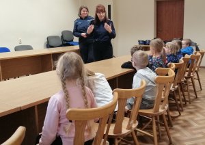 zdjęcie przedstawia dzieci z przedszkola które odwiedziły kwidzyńską komendę w tle widać dwie policjantki które omawiają zasady bezpieczeństwa w domu i poza domem.