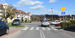 zdjęcie stojącego na skrzyżowaniu radiowozu policyjnego i dwóch samochodów które uczestniczyły w wypadku drogowym