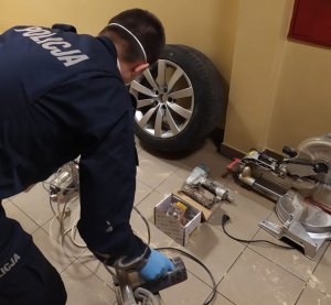 policjant rozkłada odzyskane elektronarzędzia i na podłodze