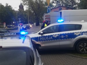 zdjęcie zrobione na kwidzyńskim rondzie, widać na nim dwa radiowozy z włączonymi światłami błyskowymi, policjanta i straż pożarną. Obok jednego z radiowozów stoi biały samochód dostawczy którego kierowca zasłabł i była mu udzielana pomoc. W dalszej części zdjęcia widać dużo jadących samochodów.