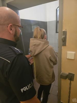 Zdjęcie, na którym policjant wprowadza zatrzymaną do PDOZ.