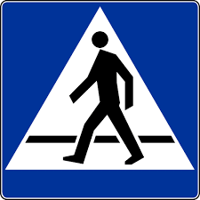 znak drogowy informujący o przejściu dla pieszych kwadratowy w niebieskim kolorze w środku biały trójkąt w którym widać przechodzącą osobę przez pasy