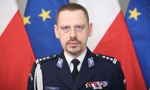 na zdjęciu widać mężczyznę w policyjnym mundurze wyjściowym na tle flagi polskiej i unii europejskiej