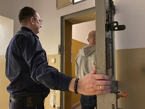 na zdjęciu widać umundurowanego policjanta który zamyka drzwi do celi do której wchodzi zatrzymany do sprawy kradzieży mężczyzna