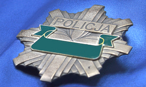 na zdjęciu widać metalową odznakę policyjną na niebieskim tle