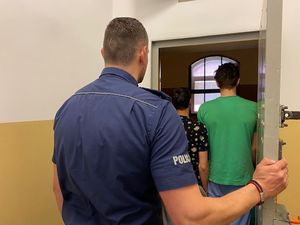 na zdjęciu widać policjanta stojącego w drzwiach do celi a przed nim dwóch zatrzymanych nastolatków do nieszczenia mienia