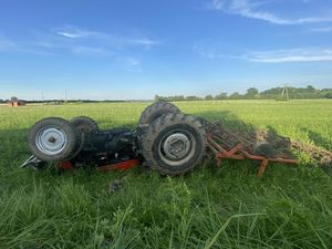 zdjęcie przewróconego traktora z podpiętym kultywatorem na polu