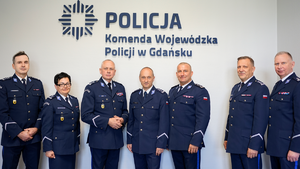 na zdjęciu widać siedmioro policjantów w nowym umundurowaniu wyjściowym tło jest szare z napisem policja komenda wojewódzka policji w gdańsku