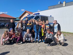 zdjęcie grupowe policjantki i dzieci które odwiedziły kwidzyńską komendę na tle radiowozu