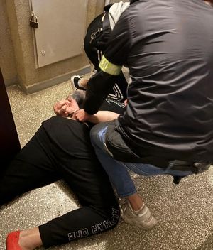 na zdjęciu widać leżącego mężczyznę na ziemi nad nim opierający się kolanem o plecy policjant który zapina mu kajdanki na rękach trzymanych z tyłu