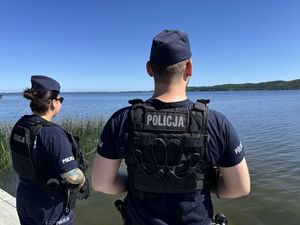 na zdjęciu widać dwoje policjantów którzy stoją nad zbiornikiem wodnym jest to jezioro bądź zatoka