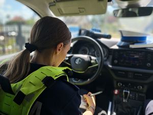 na zdjęciu widać siedzącą w radiowozie policjantkę która wypisuje mandat