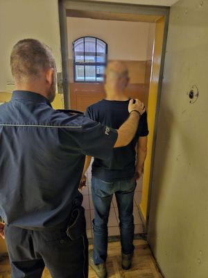Zdjęcie zatrzymanego wprowadzanego do pomieszczenia dla zatrzymanych