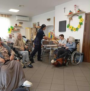 na zdjęciu widać policjantkę która rozdaje seniorom siedzącym na wózkach inwalidzkich odblaski