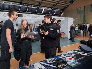na zdjęciu widać uczniów w mundurach swojej szkoły którzy stoją przy stoisku kwidzyńskich policjantów i oglądają prospekty dotyczące doboru do Policji