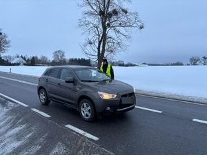 na obu zdjęciach widać policjanta dokonującego kontroli trzeźwości kierujących pojazdami policjant stoi na ulicy i kontroluje przejeżdżające auta