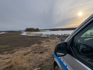 na zdjęciu widać zbiornik wodny staw i radiowóz policyjny