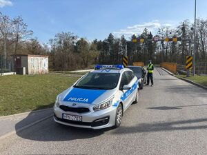 na zdjęciu widać stojący radiowóz oraz samochód zatrzymany do kontroli drogowej obok niego stoi policjant