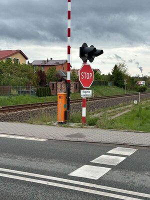 na pierwszym zdjęciu widać przejazd kolejowy z rogatkami i sygnalizacją świetlną z prawej strony widać znak STOP a pod nim tabliczkę o uszkodzeniu rogatek na drugim zdjęciu widać to samo torowisko i taki sam znak z drugiej strony przejazdu