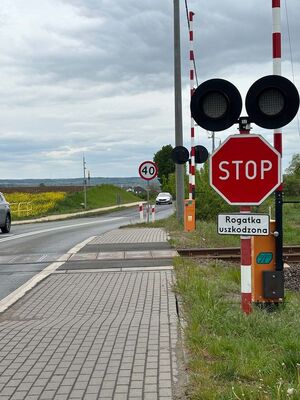 na pierwszym zdjęciu widać przejazd kolejowy z rogatkami i sygnalizacją świetlną z prawej strony widać znak STOP a pod nim tabliczkę o uszkodzeniu rogatek na drugim zdjęciu widać to samo torowisko i taki sam znak z drugiej strony przejazdu