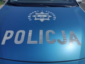 Na zdjęciu widać niebieską maskę samochodową z napisem Policja