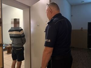 na zdjęciu widać policjanta który otwiera drzwi do celi w której widać zatrzymanego mężczyznę