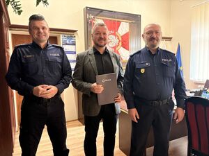 na zdjęciu widać trzech mężczyzn po bokach są dwaj policjanci komendanci po środku mężczyzna w garniturze starosta kwidzyński z dyplomem w ręku